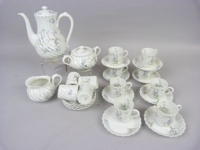 a white tea pot and cups and saucers on a table