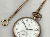 une image représentant une montre de poche en or avec une chaîne, posée sur une surface blanche