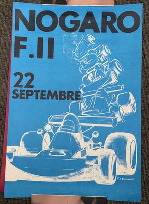 a person holding up a book with a picture of a racing car on it