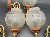 three antique wall sconces with etched glass lamps on them