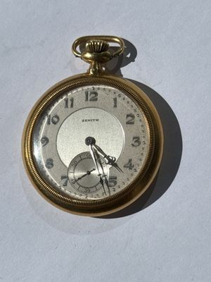 a gold pocket watch on a white surface