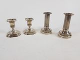 three silver candlesticks sitting on top of a white table