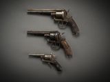 three old revolvers sitting on top of a table next to each other