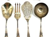 five silver spoons and two silver spoons on a white surface