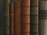 several old books are lined up on a shelf against a black background