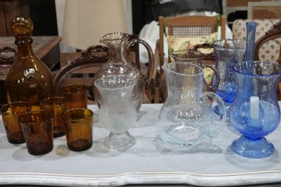 de nombreux vases et verres en verre de différentes couleurs sur la table