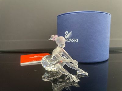 figurine en cristal représentant une femme assise sur une table, à côté d'une boîte bleue