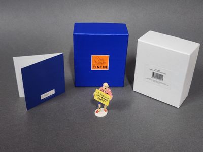 une petite figurine représentant une femme tenant une pancarte devant une boîte bleue