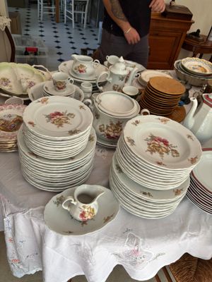 de nombreuses assiettes et tasses sur une table, avec un homme debout à l'arrière-plan