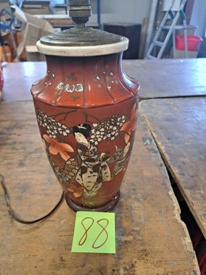 un vase rouge posé sur une table en bois, sur laquelle est accrochée une étiquette verte