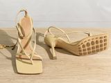 the woman ' s shoes are on the wooden floor near the wall
