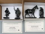 three black figurines in a cardboard box on a white surface