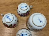 three teapots and two cups on a wooden table