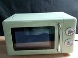 a small green microwave sitting on a wooden table
