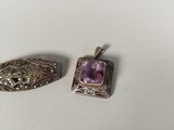 two silver pendants with amethorate stones on them