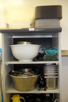 many bowls and pans on a shelf in the kitchen