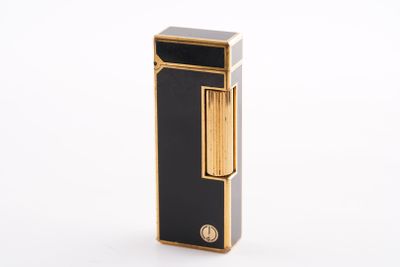 une image représentant un briquet noir et doré posé sur une surface blanche