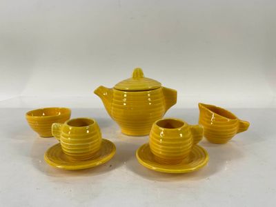 service à thé en céramique jaune, composé de tasses et de soucoupes, posé sur un fond blanc