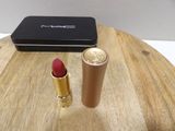 a red lipstick sitting on a wooden table next to a black box
