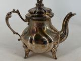 a silver teapot with a bird on top of it