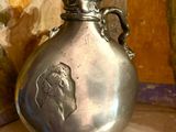 un vase en argent posé sur un sol carrelé, près d'un mur