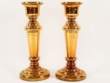 two golden candlesticks sitting on a white surface
