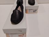 une paire de chaussures noires posée sur une boîte, elle-même posée sur une surface blanche