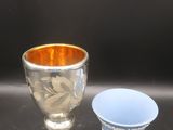 une tasse argentée et une tasse bleue posées sur une table