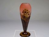 un vase en verre orné d'un motif floral, posé sur un socle