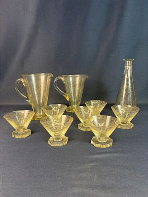 six yellow glass vases and a pitcher sitting on a table