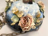 a blue and white pumpkin with flowers and a bird on it