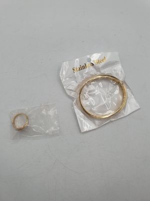 a gold bracelet and a gold ring on a white table