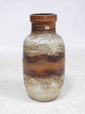 un vase brun et blanc posé sur une surface blanche