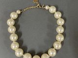 a close up of a white pearl necklace on a gray surface