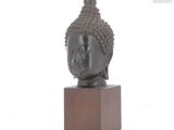 statue of a buddha head on a wooden base on a white background