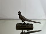 statue of a pheasant on a glass table with a white background