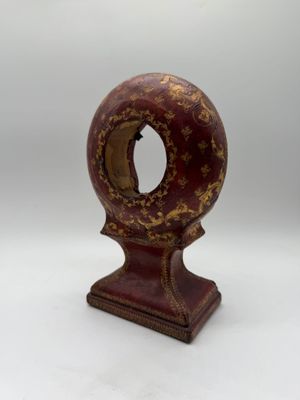 an old wooden clock with a red and gold decoration on it