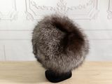 a fur hat on a wooden table with a white wall in the background