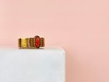 l'image d'une bague en or sertie d'une pierre rouge, posée sur un bloc