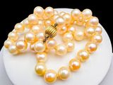 yellow pearl necklace with a gold clasp on a white plate