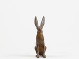 a bronze statue of a rabbit sitting on a white surface