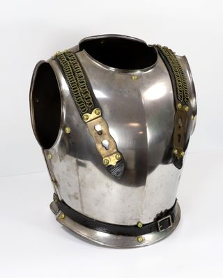 une armure argentée et dorée exposée sur un socle blanc