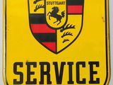 a yellow porsche service sign hanging on a white wall