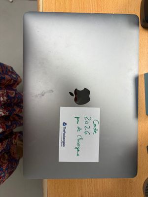 une personne assise à une table avec un ordinateur portable et un téléphone portable