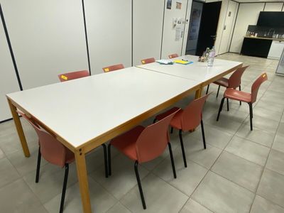 une longue table avec des chaises rouges au milieu d'une pièce