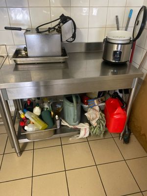 une table de travail en acier inoxydable sur laquelle sont posées une casserole et une poêle