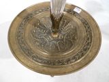 une assiette en or sur laquelle se trouve un bougeoir en verre
