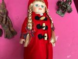 dolls on a pink table with a doll in a red coat and a doll in a red coat