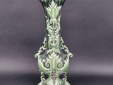 green and white vase sitting on a black surface with a gray background