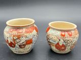 pair of small vases with designs on them sitting on a table